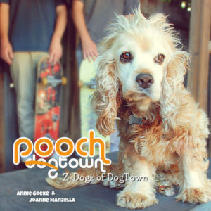 Cocker spaniel with two boys standing behind the dog with skateboards