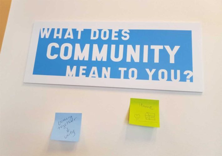 post-its on wall next to a question: What does a community mean to you?