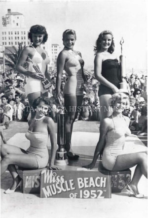 Winners of Miss Muscle Beach 1952 standing on platform with their trophies