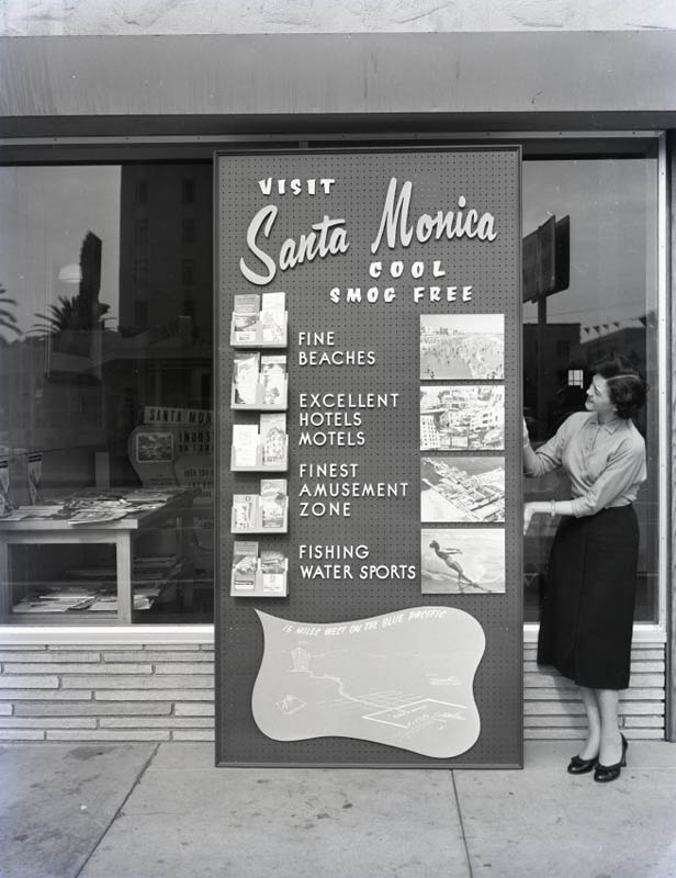 Woman standing next to a sign that reads "Visit Santa Monica"
