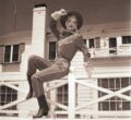 Woman in cowgirl outfit sitting on fence post (3.2.4298)